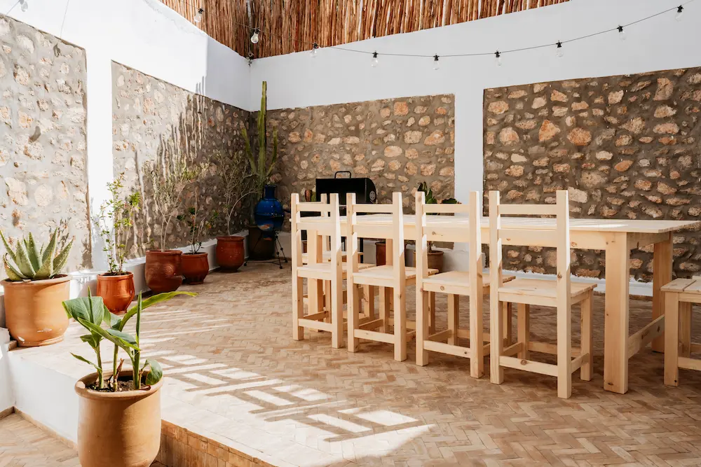 An outdoor dining table on the villa terrace, against stone walls