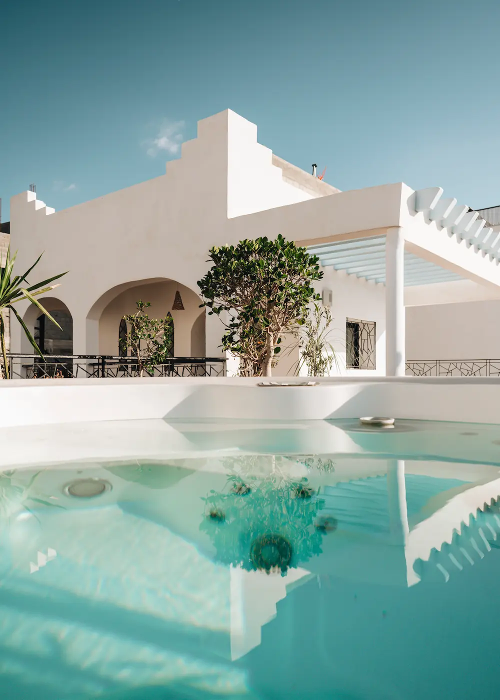 The white terrace and its plants mirrored in the surface of the hot tub